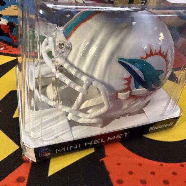 A white football helmet in its box on top of a colorful floor.